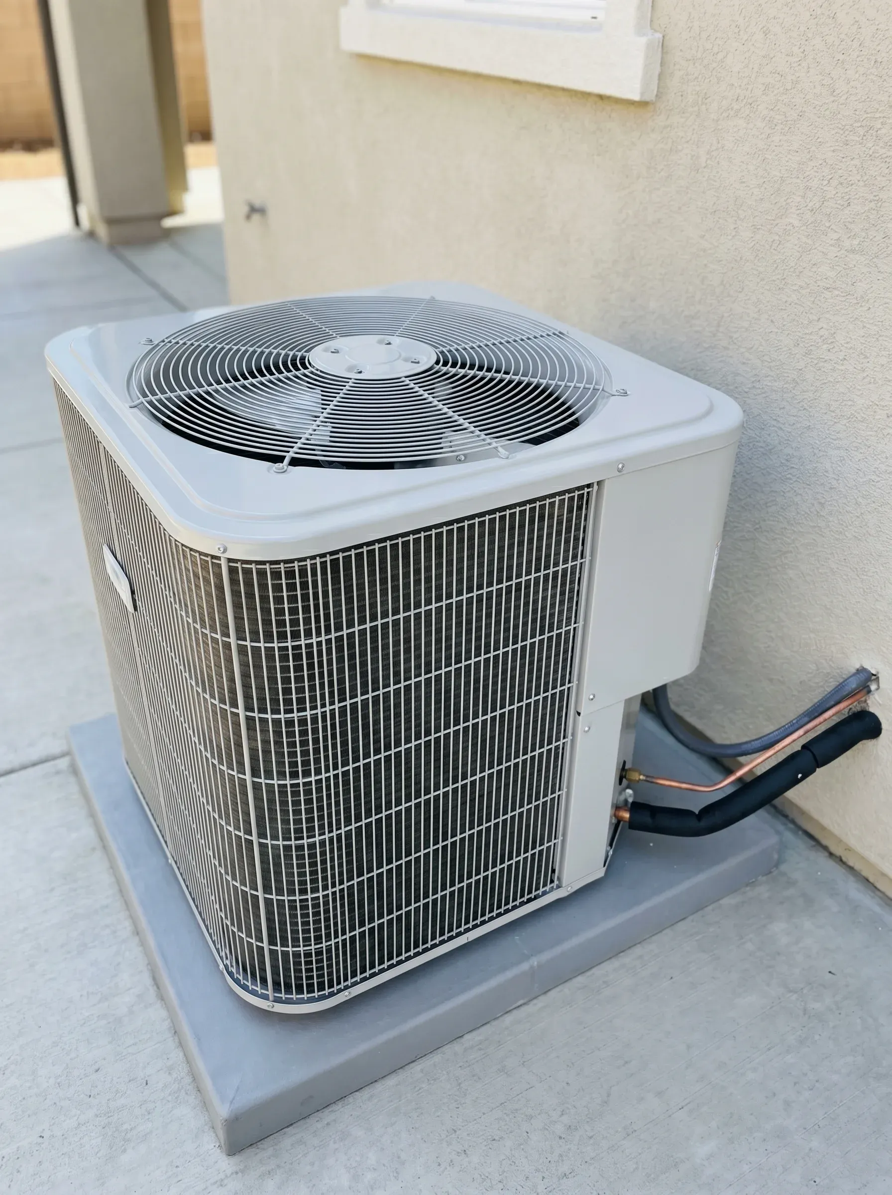 Outdoor AC condenser tucked into a Utah home's xeriscape side yard at late golden hour.